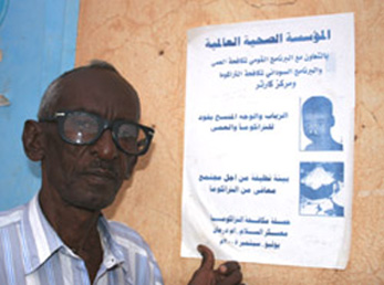 A Sudanese health worker poses in front of a trachoma poster.