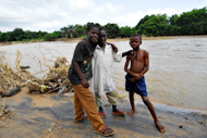 Dauda Usman (left from center), Aminu Farouk (center), and Salihu Abdullahi (right) stand in front of the reservoir they swim in three-times-a-day.