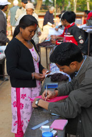 a woman presents her identification card before voting in Nepal.