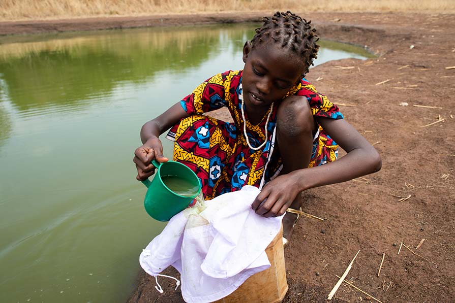 Girl pours water through a filter.