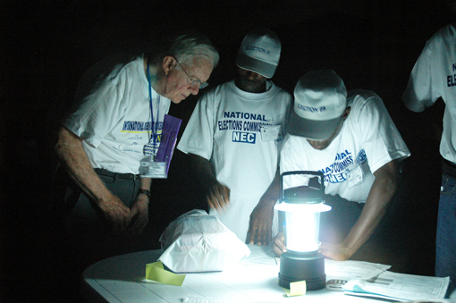 Preparing to count by lanternlight, former U.S. President Jimmy Carter observes poll closing procedures in Monrovia during Liberia's 2005 national elections.
