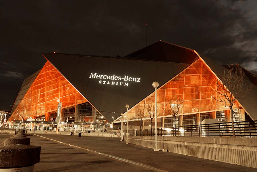 Photo of the Mercedes-Benz Stadium exterior illuminated with orange light.