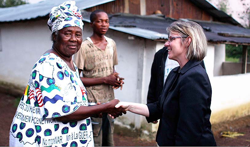 Photo of Laura Neuman shaking the hand of a woman in Liberia.