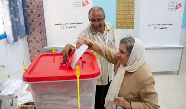 A poll worker assists an elderly woman to cast her ballot.