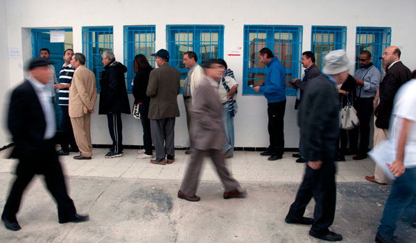 People walk to join the end of the line to vote in Tunis.