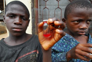 Dauda Usman, 12, holds a sample of his bright red urine, a telltale sign of schistosomiasis.