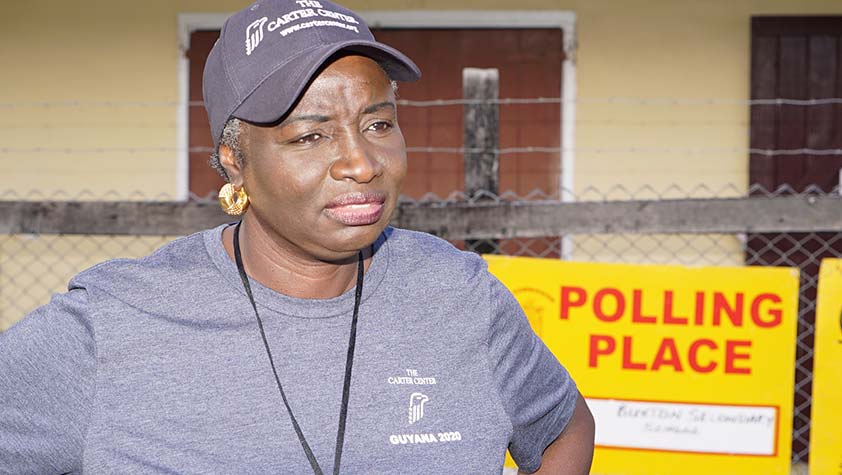 Photo of Aminata Touré at a polling place in Guyana wearing a blue Carter Center baseball cap and t-shirt.