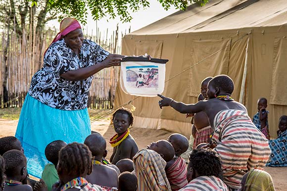 Photo of volunteer showing a chart to a small group of students.