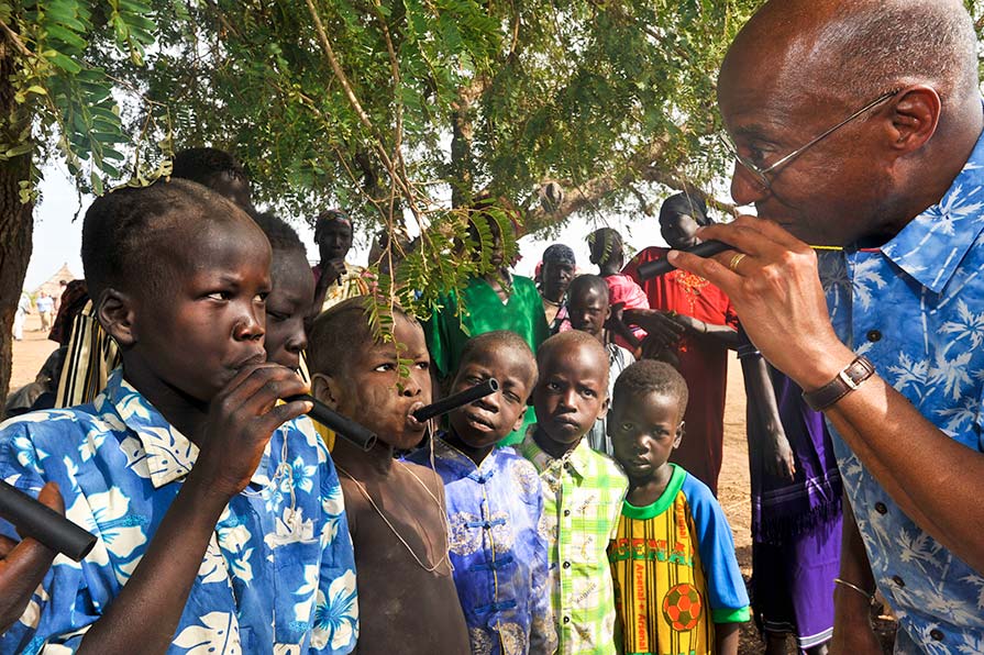 Photo of Dr. Hopkins demostrating a pipe filter to a group of children in a South Sudan village.