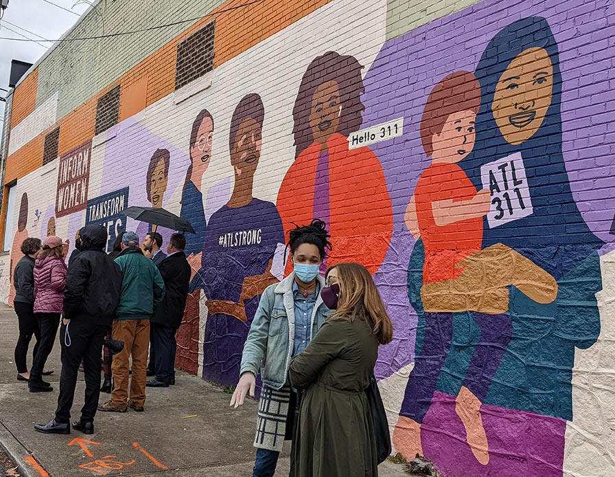 People gather in front of a mural in Atlanta to celebrate launch of a global campaign to provide information to women.