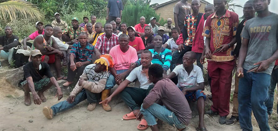 The Carter Center’s Johnny Ndebe, in red-and-white checked shirt at center, sits with traditional leaders and others blocking a bridge to protest Lofa County’s lack of representation in the Liberian Senate. 