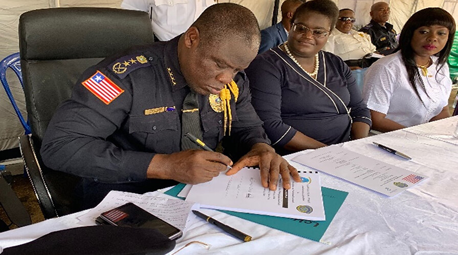 Liberia National Police Inspector General Patrick Sudue signs documents outlining new complaints and commendations procedures.