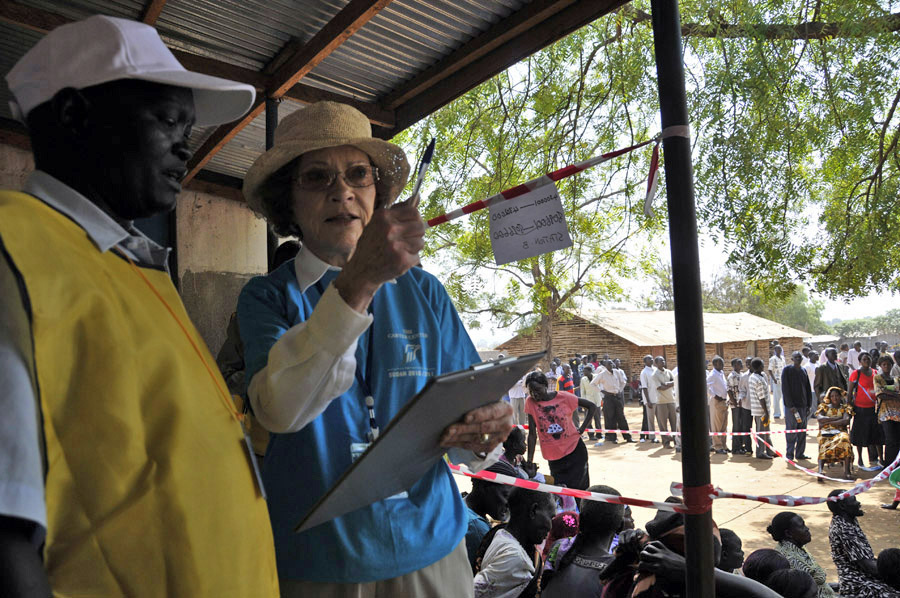Former First Lady Rosalynn Carter asks a question of a polling official on Jan. 9 in Juba, with long lines of voters behind her.