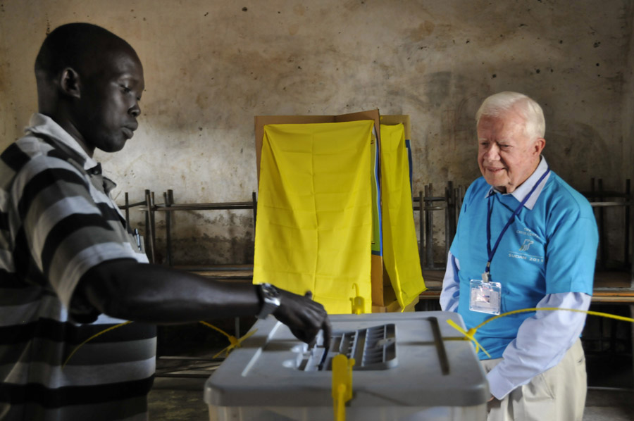 President Carter watches a man vote on Jan. 9.
