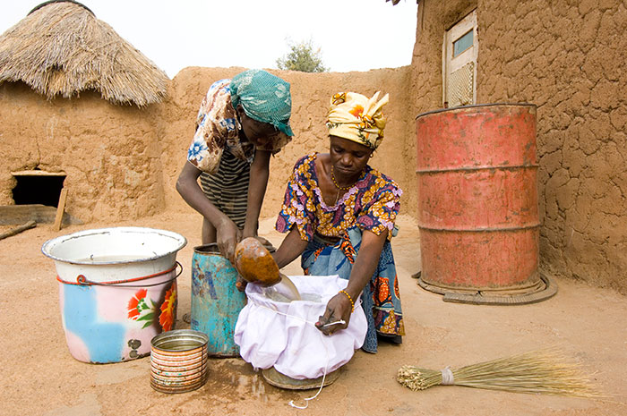 Photo of a Women use a cloth filter to strain water at home.