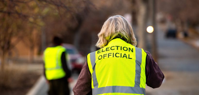 Photo of an election official wearing a neon yellow safety vest with the phrase 'election official' on the back.