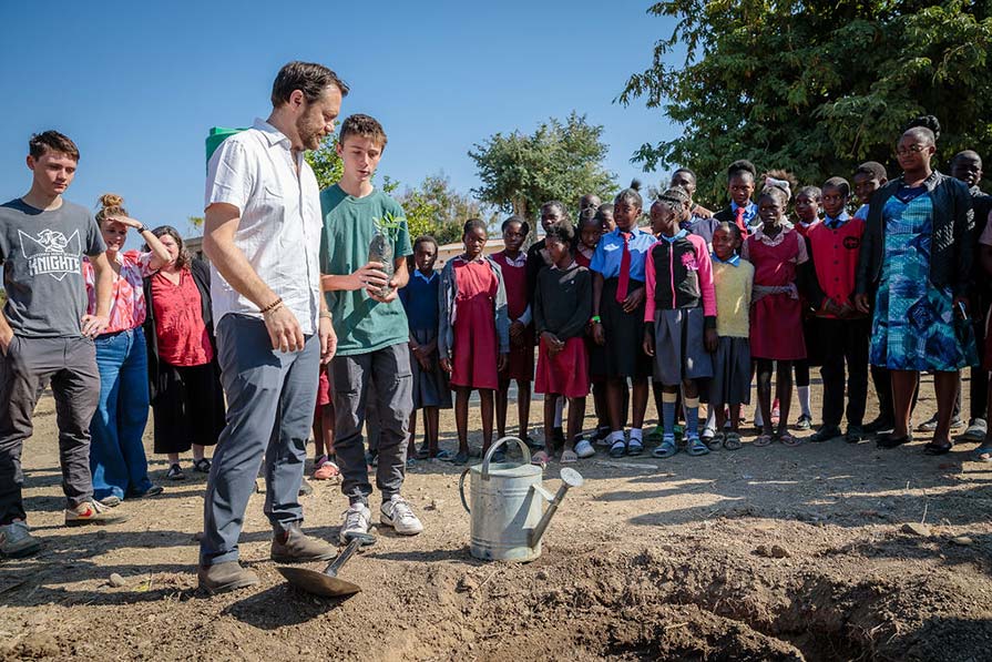 Jason Carter and son prepare soil as Zambian children look on.