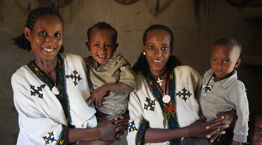 Two women in Ethiopia hold children on their hips.