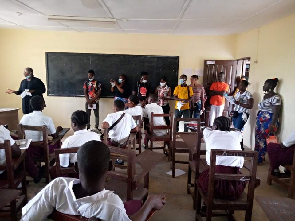 Youth ambassadors in Liberia speak to students in a classroom.