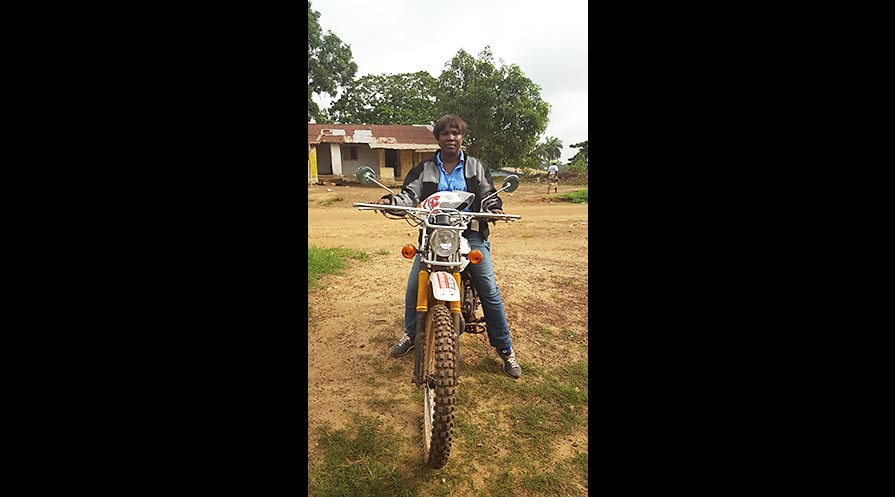 Borbor on her trusty motorbike, which she uses to travel from community to community in Liberia, teaching citizens about the law and serving as a mediator.