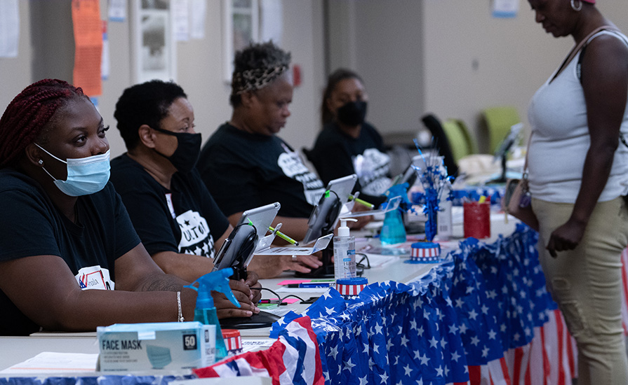 Election workers check in voters at a desk.