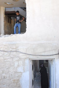 Ahmed Said looks down at what remains of the second floor of his family's home, while his mother walks away.