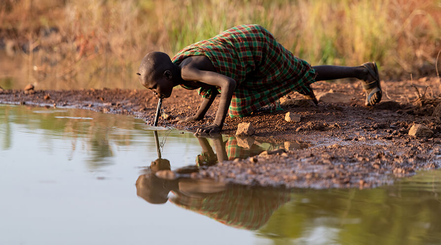 A village resident in South Sudan’s Eastern Equatoria State uses a pipe filter to drink water safely. The device filters out tiny crustaceans that harbor Guinea worm larvae. 