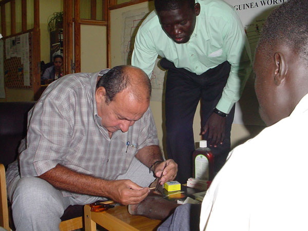 In this photo from 2002, Nabil works to remove a Guinea worm from the ankle of a man.