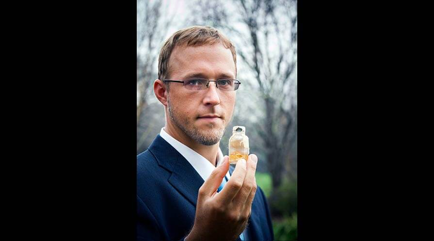 Weiss holds up a Guinea worm in a glass jar.