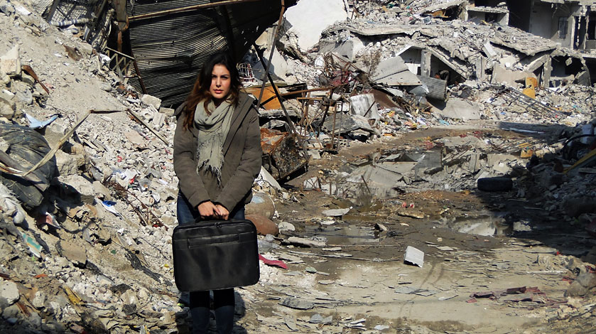 Abeer Pamuk stands in front of ruins in Aleppo.