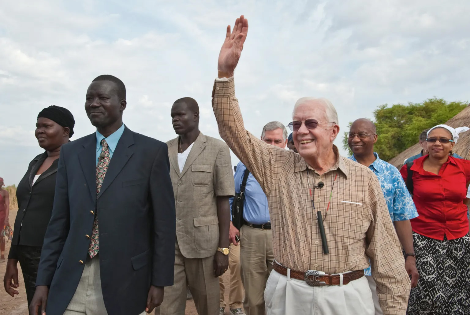 Jimmy Carter waves to crowd while walking alongside Makoy Samuel Yibi.