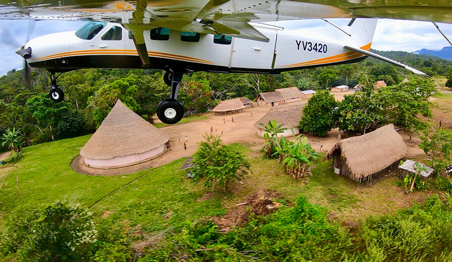 A plane flies over a Yanomami community.