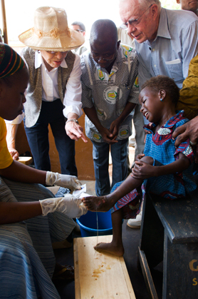 Former U.S. President Jimmy Carter and his wife, Rosalynn, watch as a Guinea worm health worker dresses a child's extremely painful Guinea worm wound.