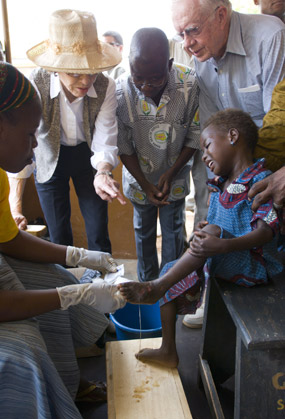 Jimmy and Rosalynn Carter watch as a health worker dresses a child's Guinea worm wound.