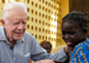 Former U.S. President Jimmy Carter tries to comfort 6-year-old Ruhama Issah at Savelugu Hospital as a Carter Center technical assistant dresses Issah's extremely painful Guinea worm wound.