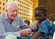 Former U.S. President Jimmy Carter comforts six-year-old Ruhama Issah as Adams Bawa, a Carter Center technical assistant, dresses her extremely painful Guinea worm wound. 