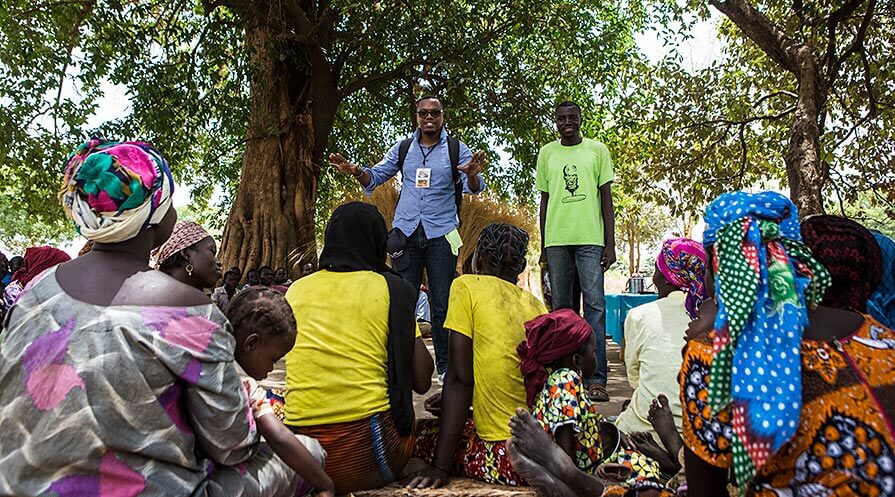 Dr. Hubert Zirimwabagabo, in blue shirt, teaches a group of women in Chad about Guinea worm disease and what they can do to prevent it. 