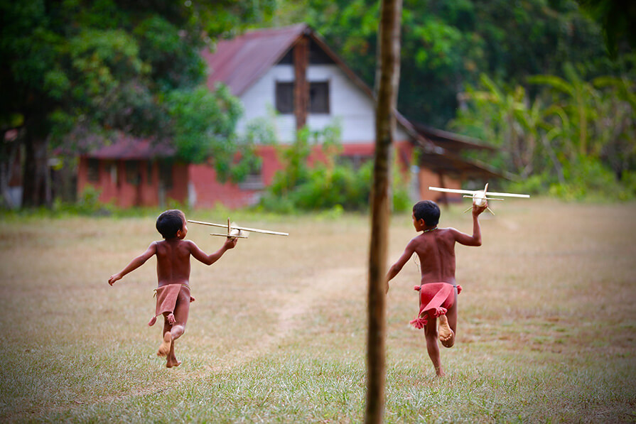 Yanomami children running with toy airplanes 