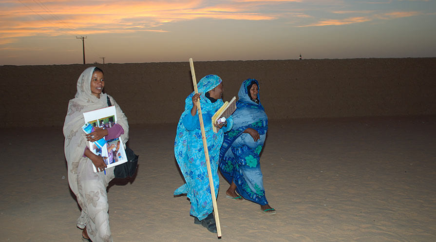 Above, community health workers carry educational materials in northern Sudan.