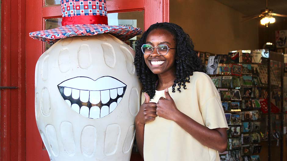 Intern stands next to a peanut statue.