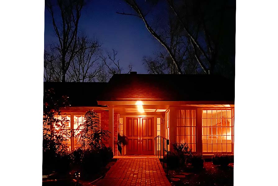 Photo of the front exterior of the Carters' home illuminated with orange light.