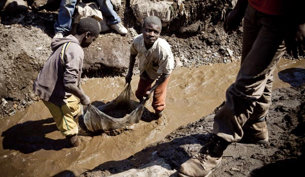 In the open copper mine in Kamatanda, DRC, children often spend 10 hours washing and sorting the ore in water and mud for less than two dollars a day. (Photos by G. Dubourthoumieu/The Carter Center)